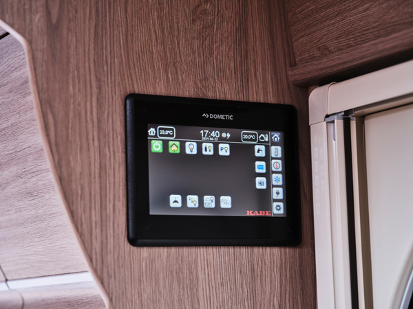 En digital kontrollpanel från Dometic i en KABE-husbil, monterad på träinredningen. Systemet gör det enkelt att styra belysning, temperatur och andra funktioner