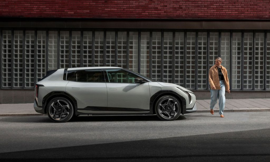 Kia EV4 parkerad på stadsgata med person intill – elbilen som passar det urbana livet.